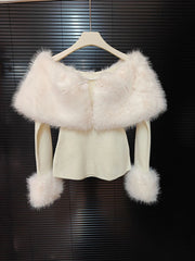 White fur shrug over a white top on a hanger against a dark background