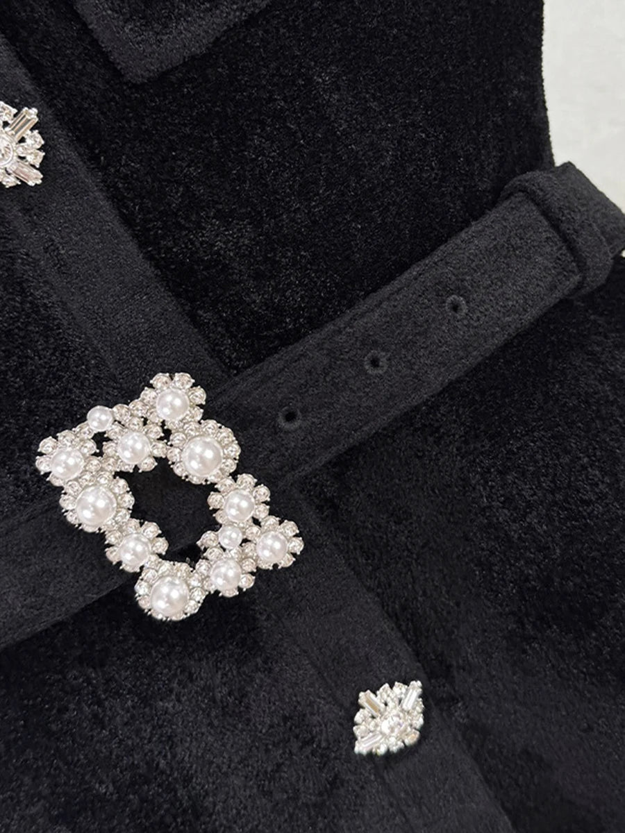Close-up of a black coat with decorative buttons featuring pearls and crystals.