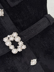 Close-up of a black coat with decorative buttons featuring pearls and crystals.