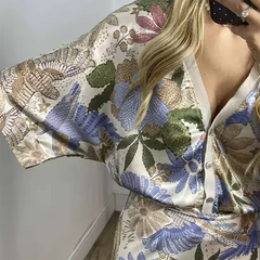 Person wearing a floral patterned kimono-style garment with a plain background