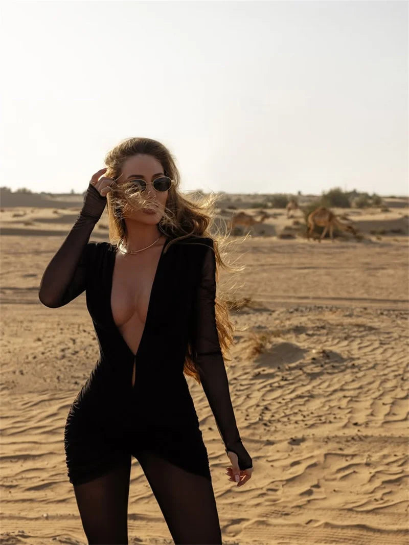 Woman in a black outfit standing in a desert landscape