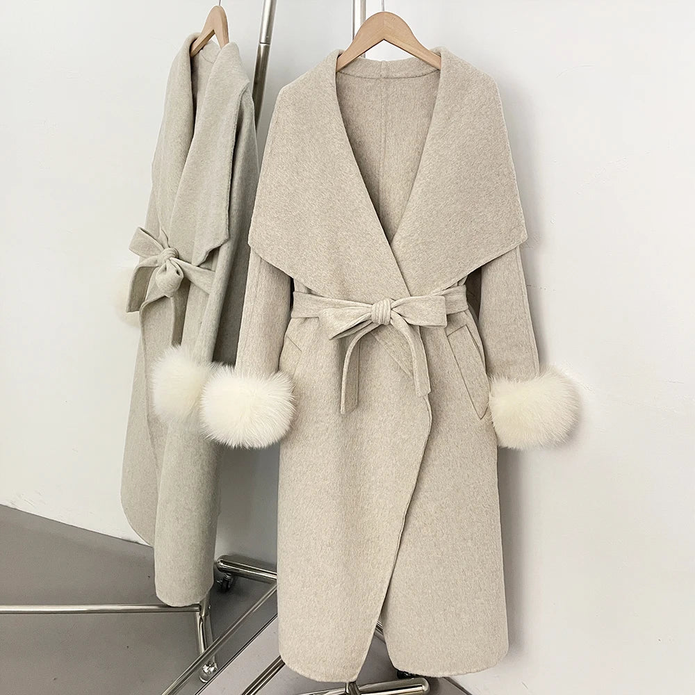 Beige wool blend coat with white fur trim and a belted waist.