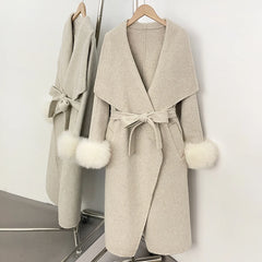 Beige wool blend coat with white fur trim and a belted waist.