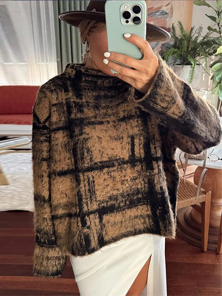 Person wearing a plaid sweater taking a mirror selfie in a room with furniture and plants.