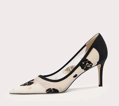 Black and white high-heeled shoe with floral design on a light gray background