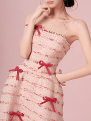 Woman wearing a strapless dress with red bows on a pink background