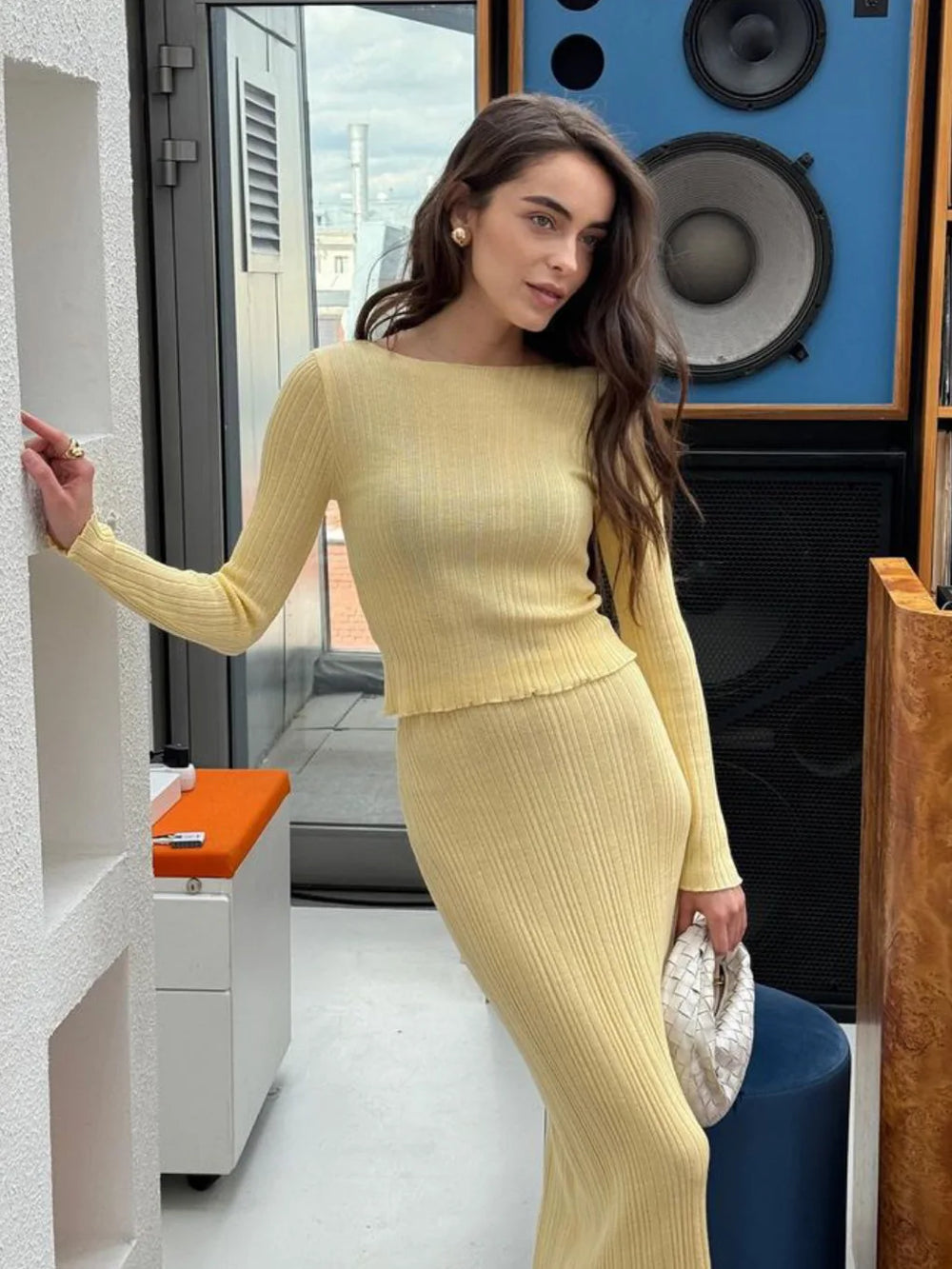 Woman in a yellow outfit standing indoors with modern decor.