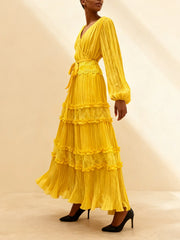 Yellow tiered dress worn by a model on a beige background