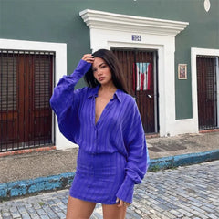 Woman in a purple outfit standing on a street with a building in the background
