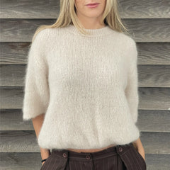 Person wearing a cream sweater against a wooden background
