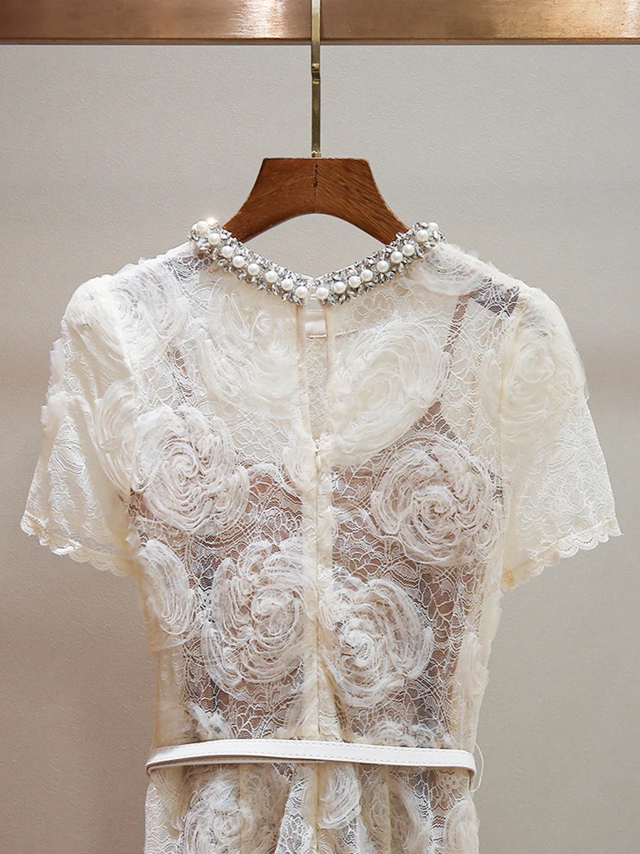 White lace top with floral embroidery on a wooden hanger against a neutral background