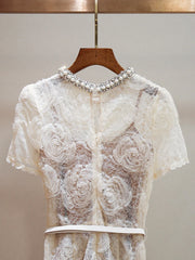 White lace top with floral embroidery on a wooden hanger against a neutral background