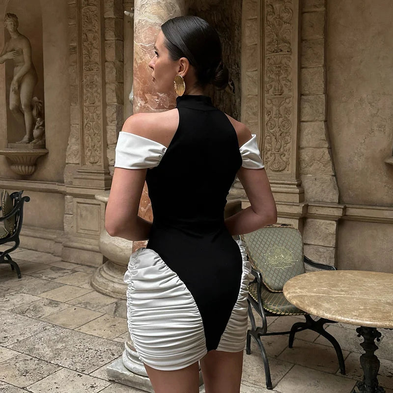 Woman in a black and white outfit standing in an outdoor setting with classical architecture.