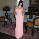 Woman in a pink dress standing in an elegant room with floral patterns and furniture.