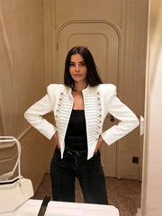 Woman wearing a white cropped military style jacket with gold buttons and cord braiding