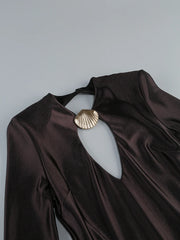 Brown garment with a gold brooch on a gray background