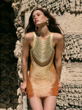 Woman wearing a gold and orange outfit against a textured stone wall.