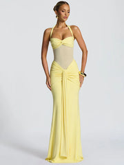 Woman wearing a yellow and beige evening gown on a plain background