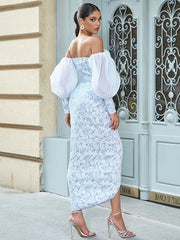 Woman in a light blue floral dress with white sleeves standing in front of an ornate door.