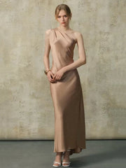 Woman wearing a one-shoulder maxi dress with a draped neckline and floor-length hem