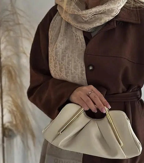 Person holding a beige handbag with a neutral background