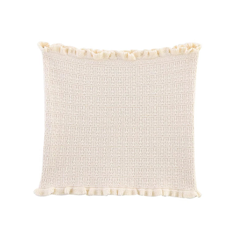 Textured cream pillow with ruffled edge on a white background