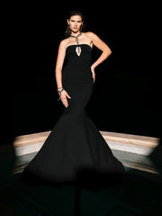 Woman wearing a black strapless gown with a mermaid silhouette on a dark background