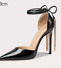 Black high-heeled shoe with a gold chain on a light gray background