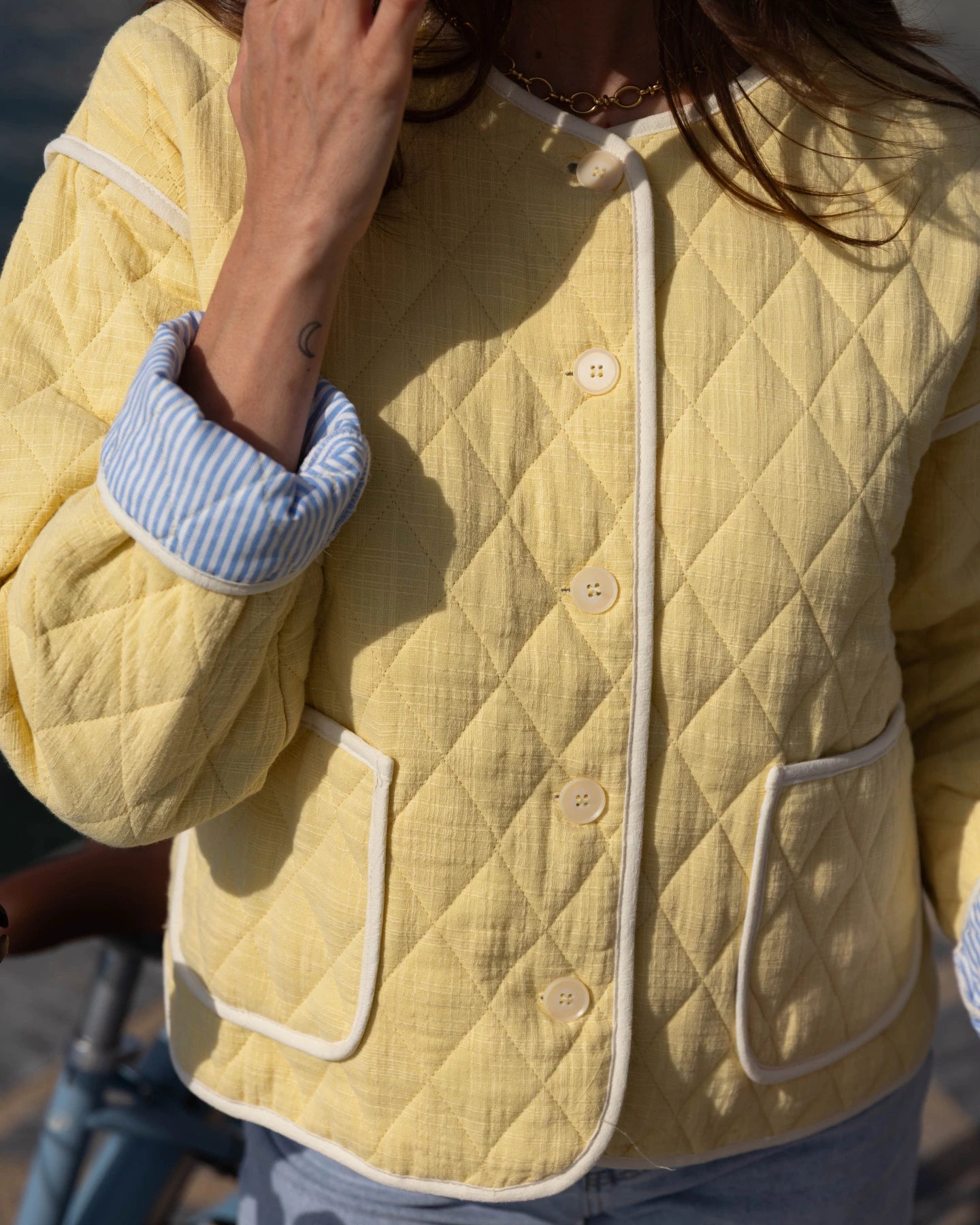 Person wearing a yellow quilted jacket with white buttons and trim.
