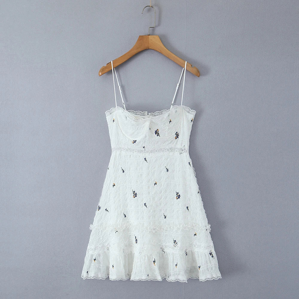 White lace dress with floral embroidery on a wooden hanger against a gray background