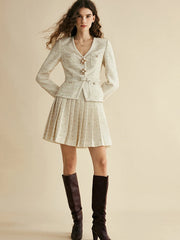 Woman wearing a patterned dress with a jacket and knee-high boots on a beige background