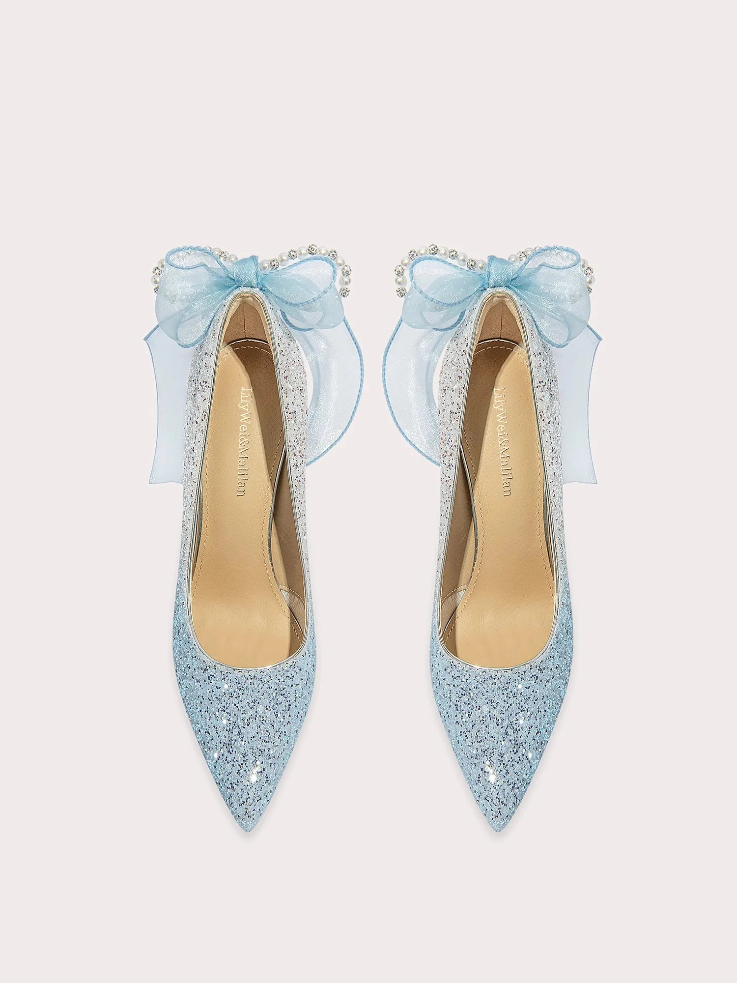 Pair of light blue glittery high heels with decorative bows on a white background