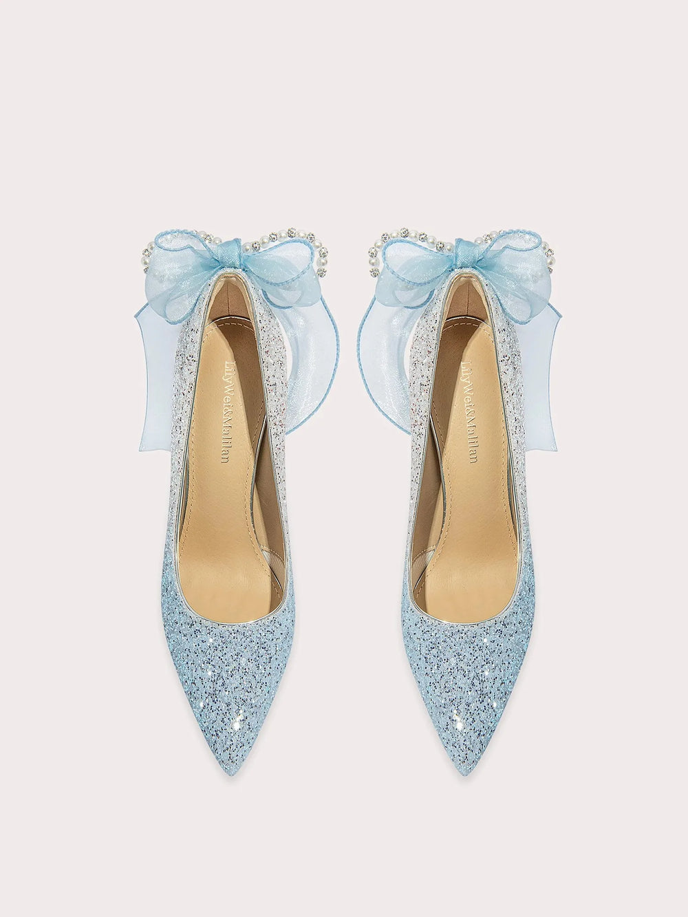Pair of light blue glittery high heels with decorative bows on a white background