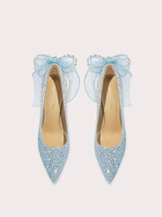 Pair of light blue glittery high heels with decorative bows on a white background