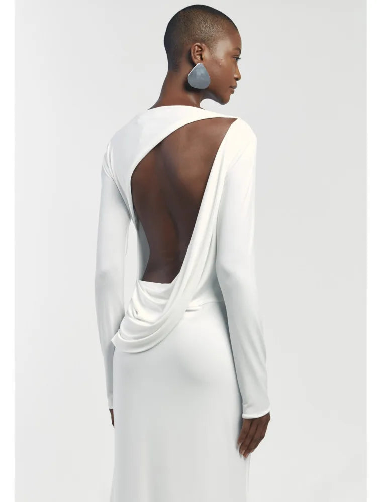 Woman wearing a white dress with a backless design on a plain background