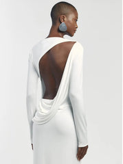 Woman wearing a white dress with a backless design on a plain background