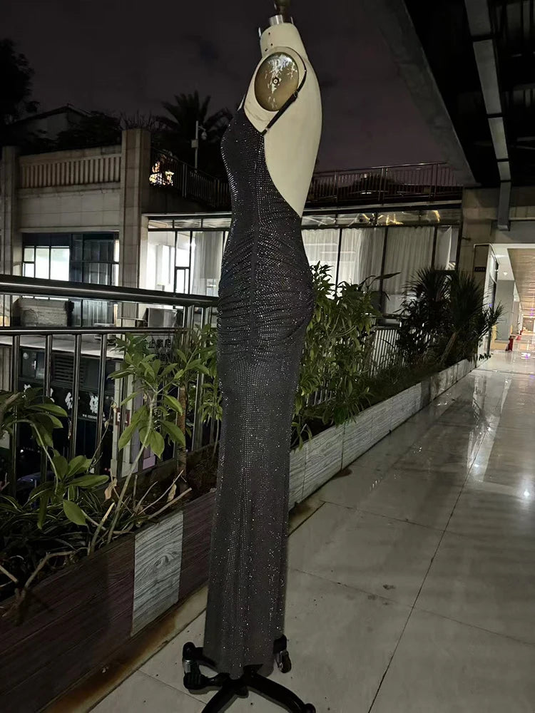 Mannequin wearing a long, dark evening gown with a light-colored top in an outdoor setting.