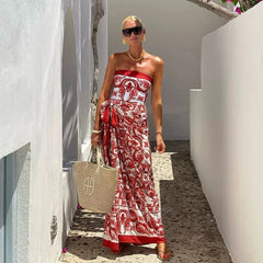 Woman in a red and white printed strapless top with a sarong-style skirt in a narrow alleyway.