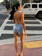 Woman in a sequin outfit crossing a street at a crosswalk.