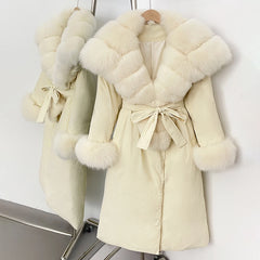 Cream-colored coat with fur trim on a rack against a white background