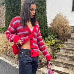 Woman wearing a red and pink striped cardigan outdoors.