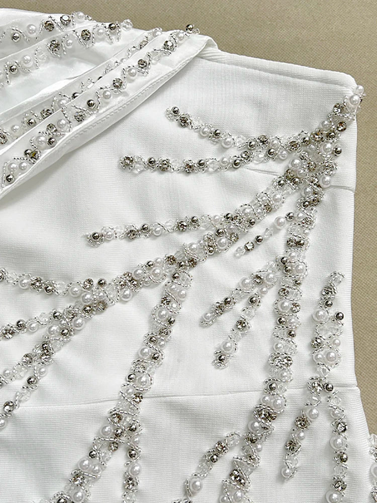 White garment with intricate beadwork on a beige background