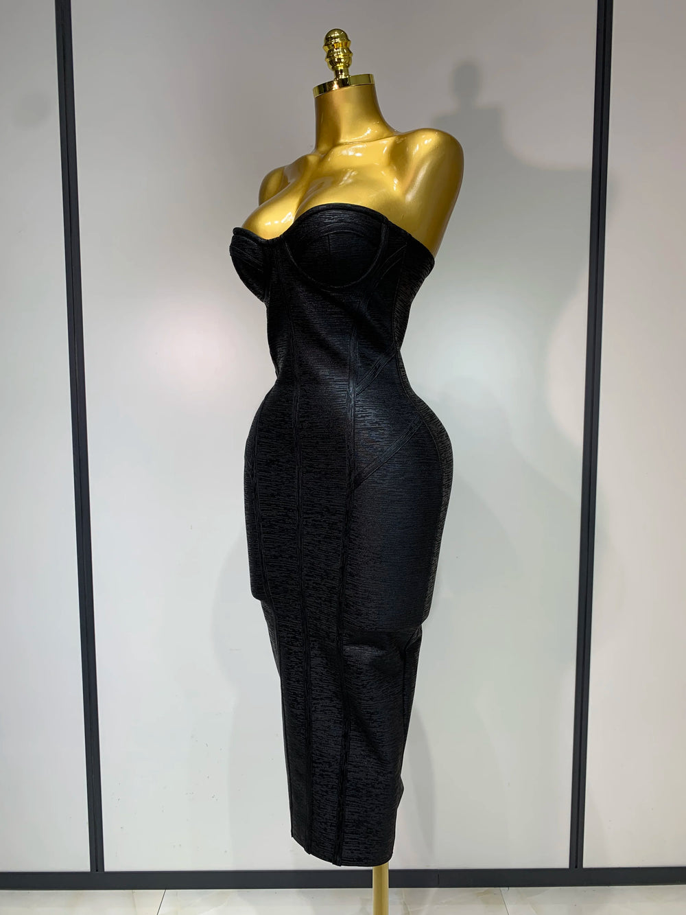 Black evening gown on a gold mannequin against a white background
