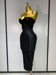 Black evening gown on a gold mannequin against a white background