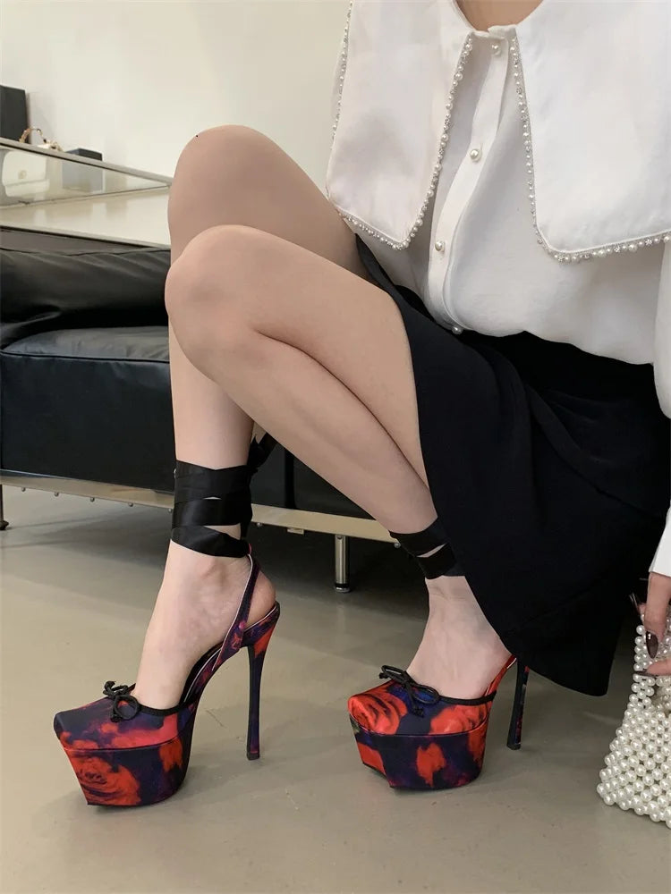 Person wearing high-heeled platform shoes with a colorful design, sitting on a chair.