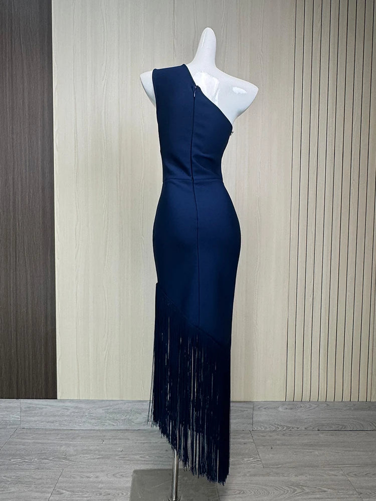 Navy blue dress with fringe details on a mannequin against a striped wall.