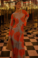 Woman in a floral dress standing in a reflective, mirrored room with black and white checkered floor.