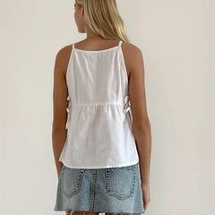 Person wearing a white tank top and denim skirt on a plain background