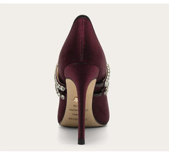Maroon high-heeled shoe with embellishments on a white background