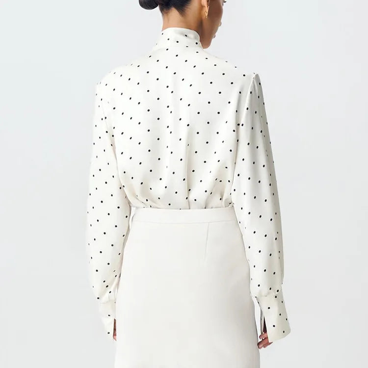 White blouse with black polka dots on a plain background